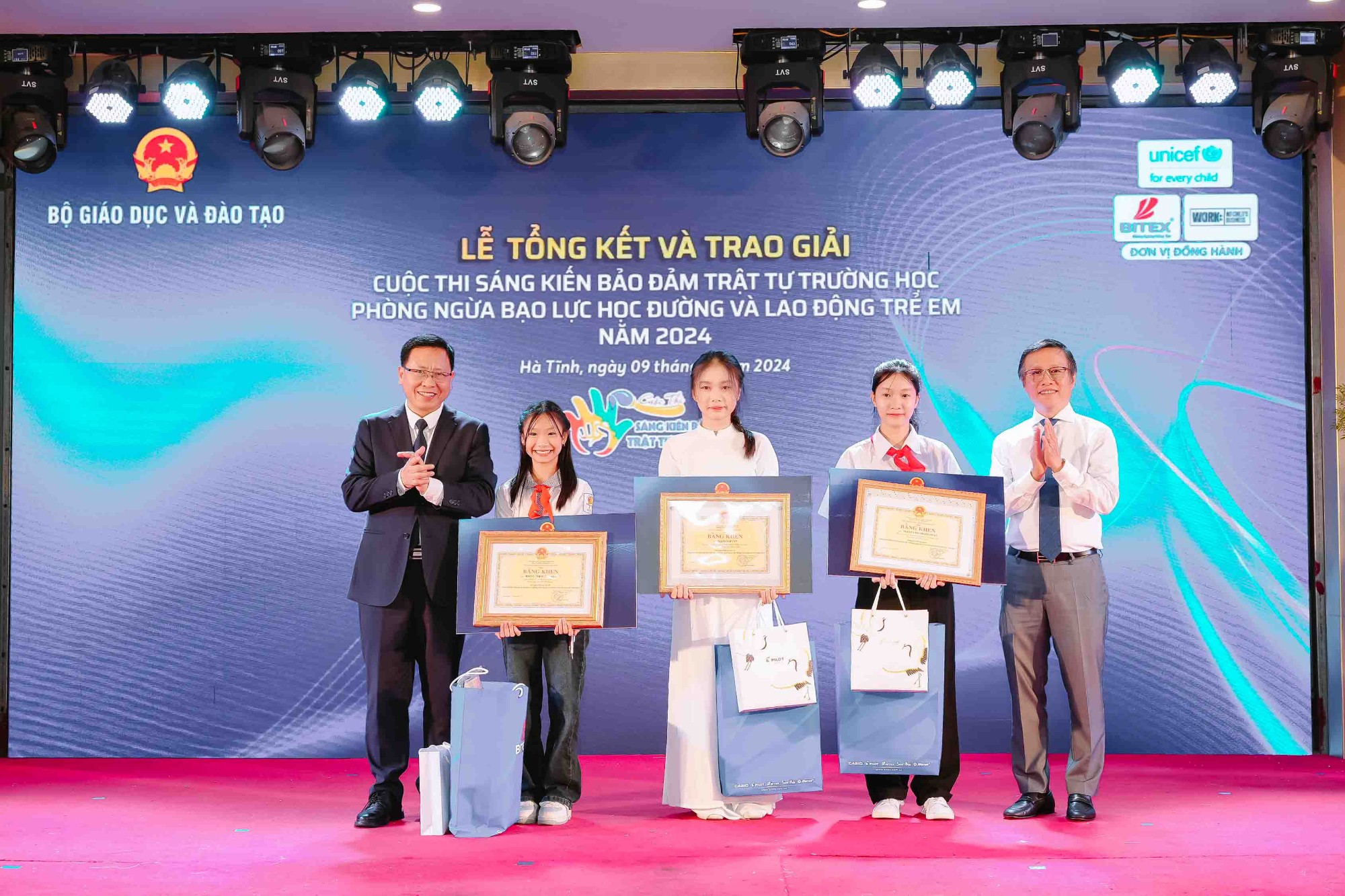 Ông Trần Văn Đạt, Vụ trưởng Vụ Giáo dục Chính trị và Công tác học sinh sinh viên (ngoài cùng bên trái) và ông Nguyễn Xuân Dũng, Chủ tịch HĐQT Công ty BITEX (ngoài cùng bên phải) cùng trao quà và bằng khen cho các em thí sinh xuất sắc đạt giải nhất ở các cấp Tiểu học, THCS và THPT